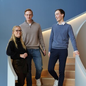 Drei Azubiblogger stehen auf einer geschwungenen, modernen Treppe