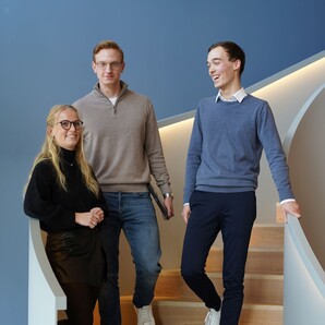 Drei Azubiblogger stehen auf einer geschwungenen, modernen Treppe