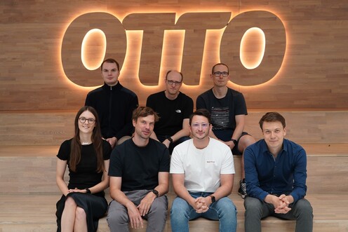 Team Jarvis sitzt auf Stufen vor dem OTTO-Logo und lächelt in die Kamera
