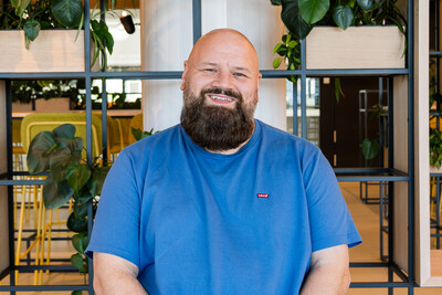 Foto von Techblog-Autor Jan in einem blauen Shirt, sitzend vor einem Regal mit Pflanzen