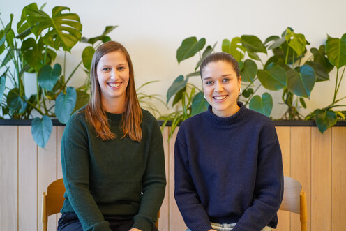 Tech-Blog Autorinnen Aemilia Klingelhöfer & Svenja Lippke Zwei weibliche Autorinnen vor einer Wand mit Pflanzen in warmem Licht