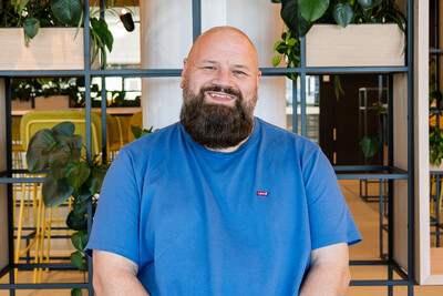 Foto von Techblog-Autor Jan in einem blauen Shirt, sitzend vor einem Regal mit Pflanzen