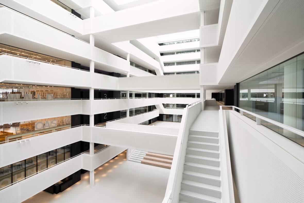 Das lichtdurchflutete Atrium im OTTO-Headquarter. Unten befindet sich der Eingang und Sitzreihen für Vorträge und Veranstaltungen. Die Mitte des Gebäudes ist offen, die Arbeitsflächen und Räumlichkeiten befinden sich am Rand des Gebäudes. 