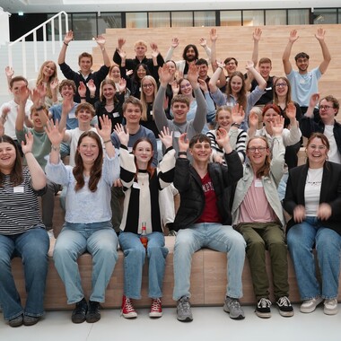Unsere neuen Azubis 2025, die jubelnd auf einer Treppe im OTTO Headquarter sitzen