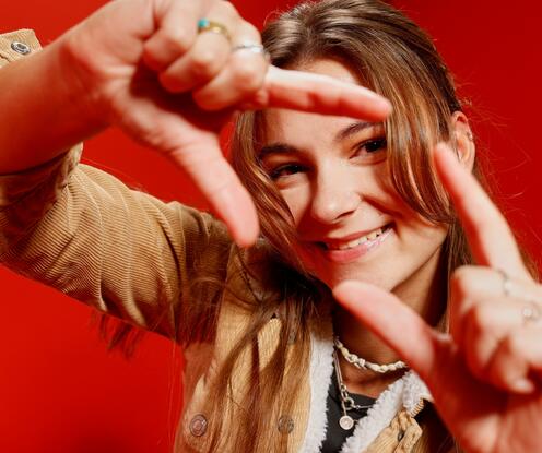 Unsere Kollegin absolviert eine Ausbildung zur E-Commerce-Managerin bei OTTO. Beim Living-Red-Shooting hält sie ihre Hände in Form eines Quadrats in die Kamera, sodass ihr Gesicht zu sehen ist.