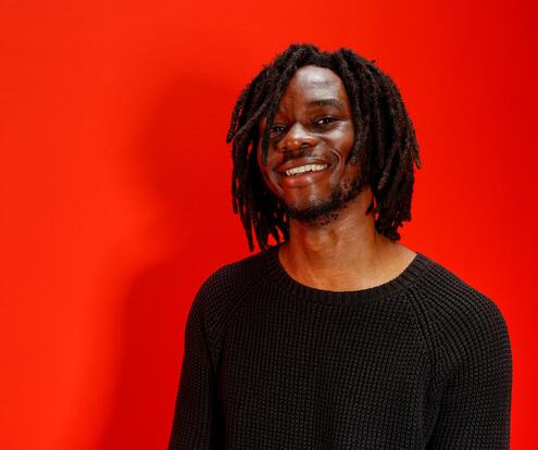 Azubi der Fachinformatik für Daten- & Prozessanalyse bei OTTO ist beim Living Red Shooting und lächelt in die Kamera.