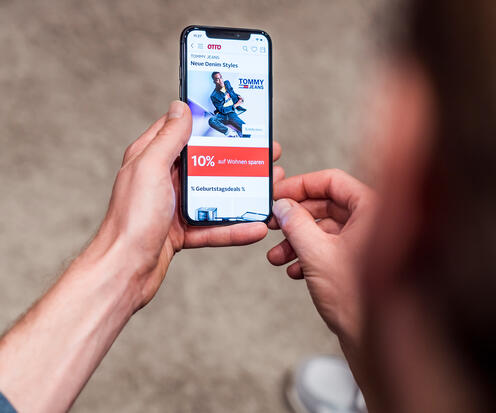 OTTO App Eine Person ist am Handy, hat die OTTO-App geöffnet und scrollt.