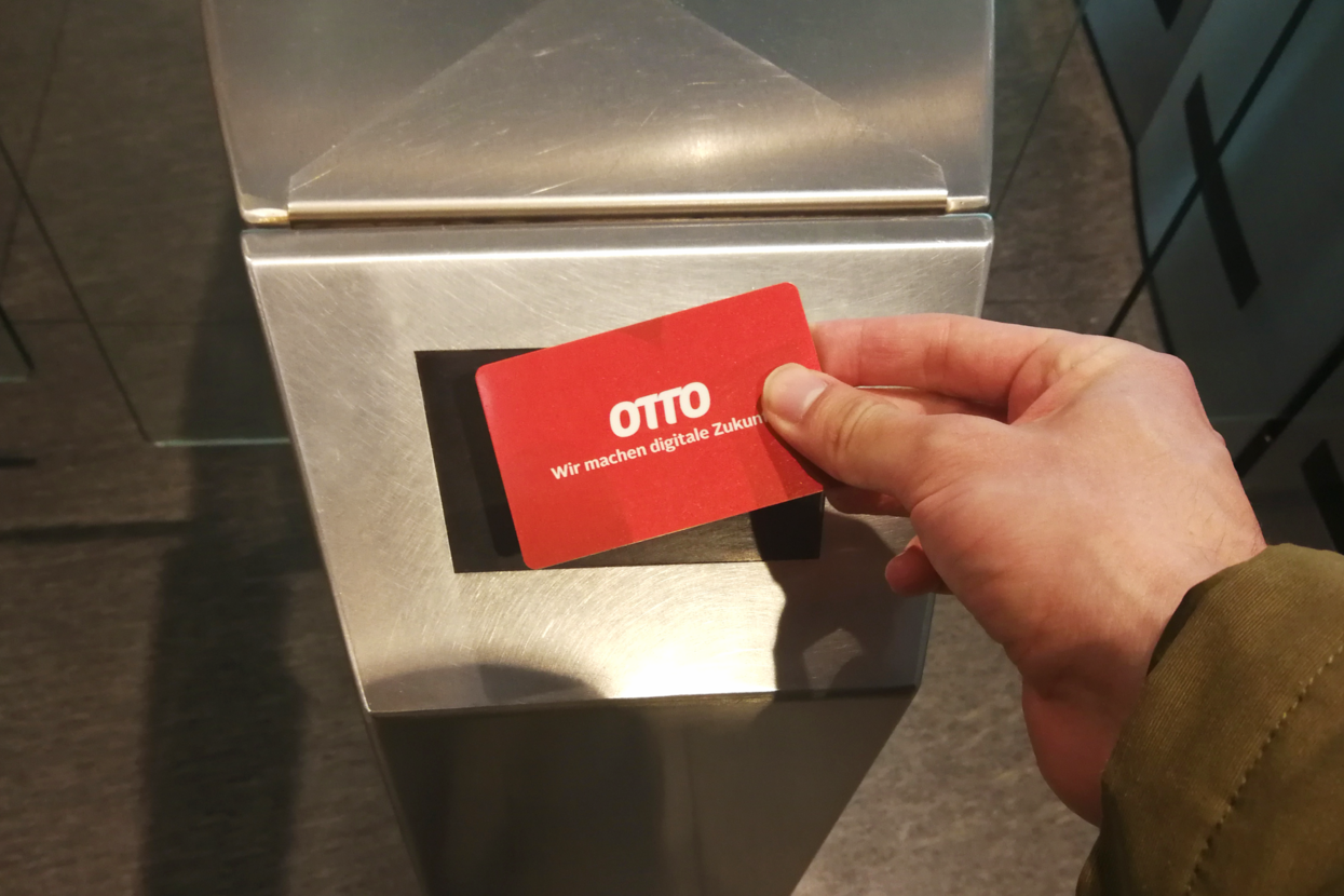 Der Mitarbeiterausweis von OTTO wird am Stempelgerät angebracht, um die Arbeitszeit zu erfassen.