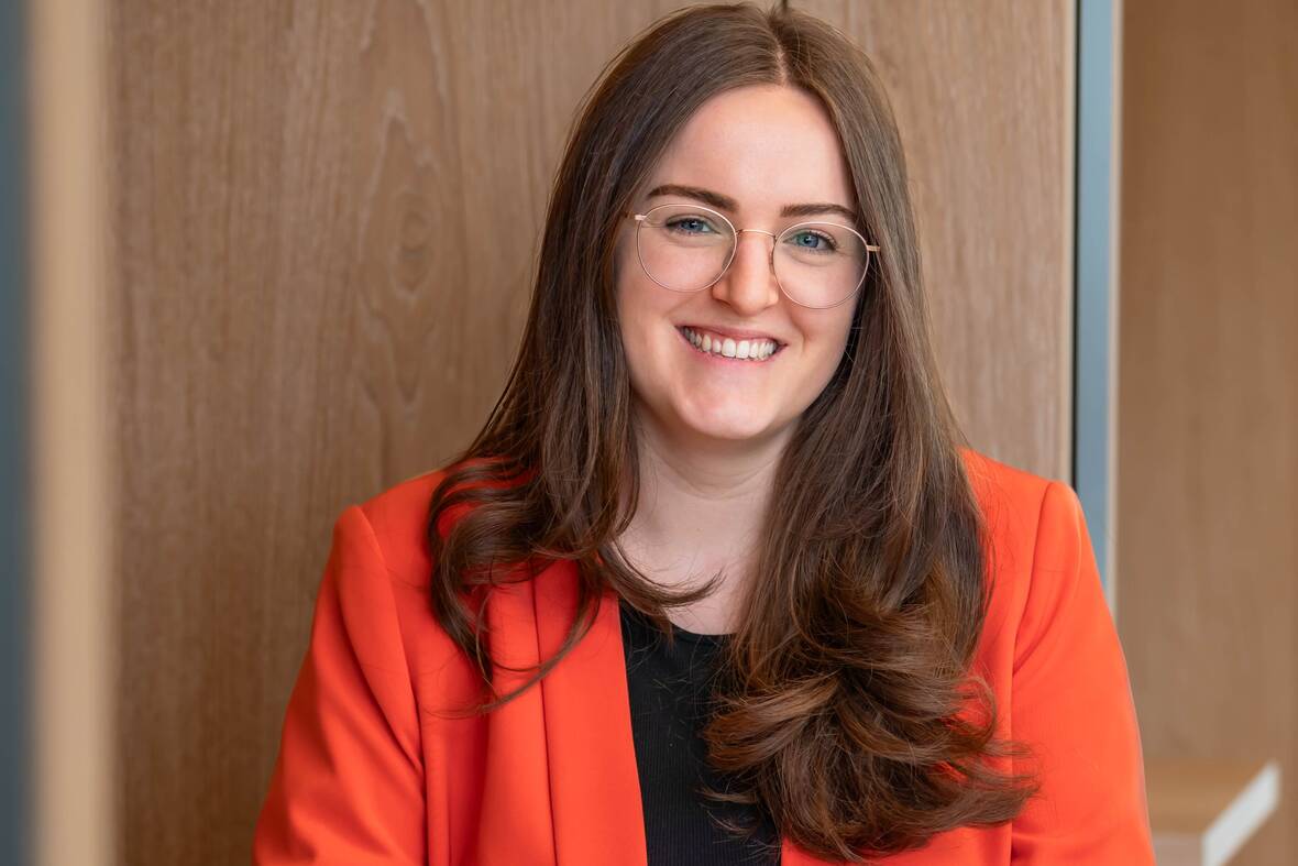 Michelle, Recruiterin bei OTTO, sitzt lächelnd im Social Space auf dem OTTO Campus