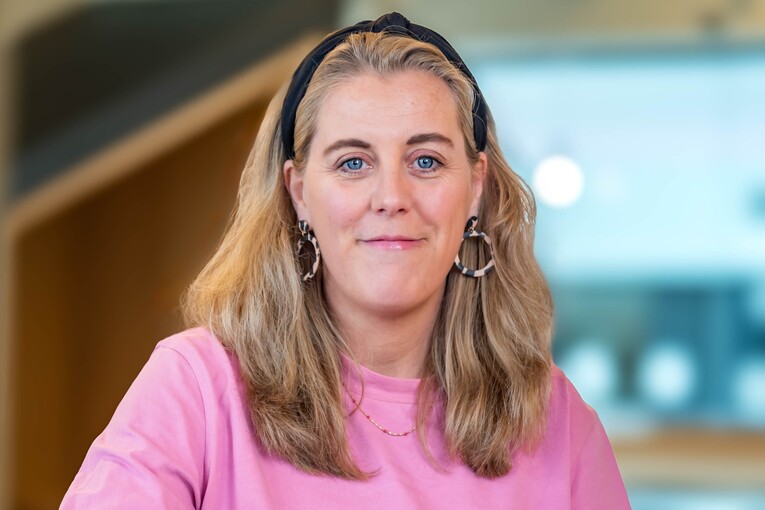 Hannah, Recruiterin bei OTTO, im Social Space auf dem OTTO Campus und lächelt in die Kamera.