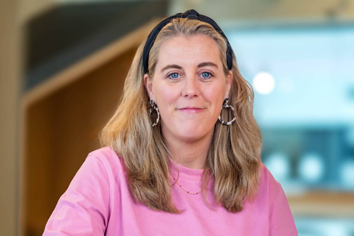 Hannah, Recruiterin bei OTTO, im Social Space auf dem OTTO Campus und lächelt in die Kamera. 