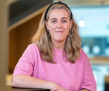 Hannah, Recruiterin bei OTTO, im Social Space auf dem OTTO Campus und lächelt in die Kamera. 