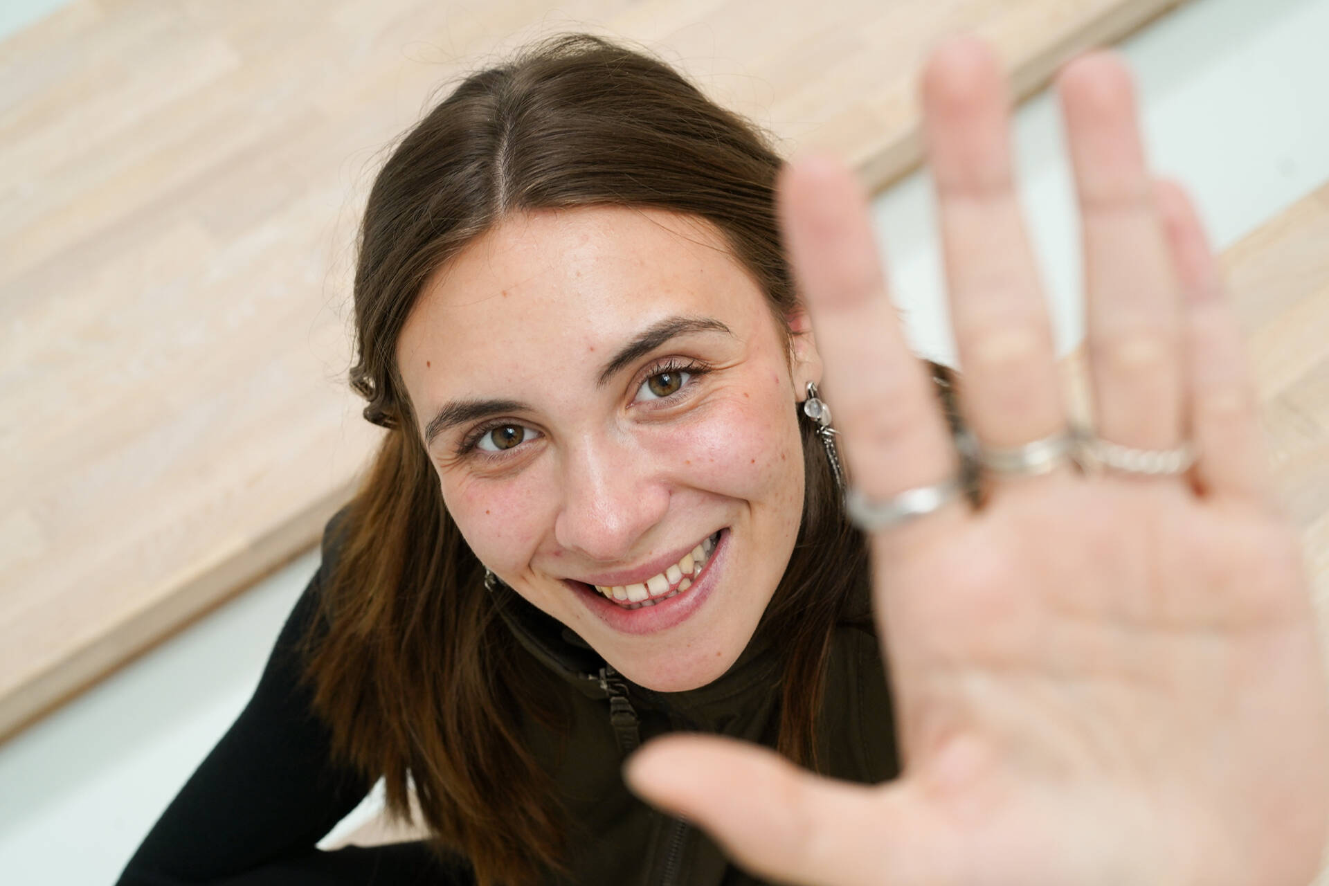 Unsere Werkstudentin sitzt auf dem Boden lächelt und greift in die Kamera.