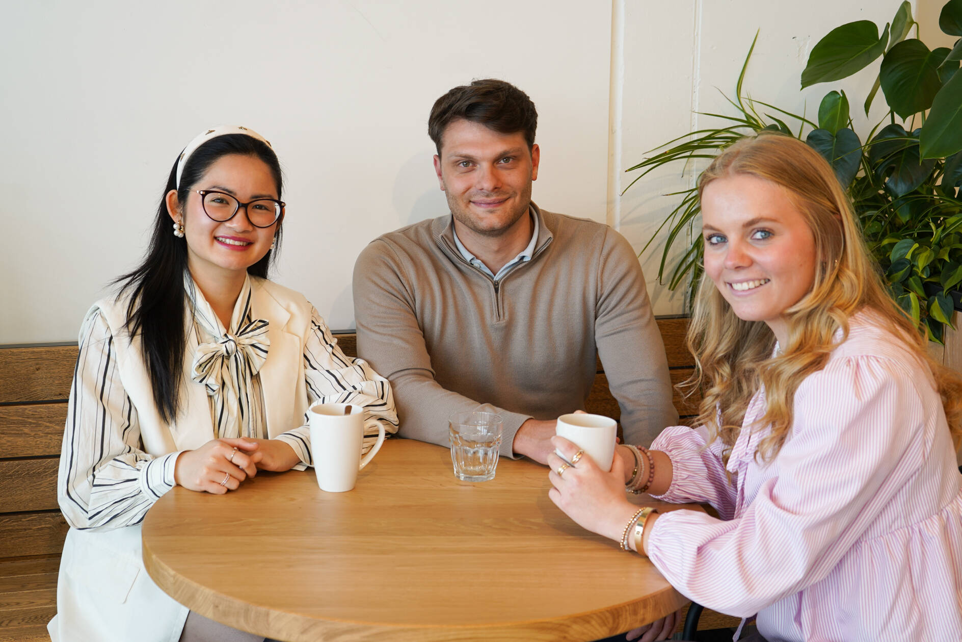 Drei unserer Werkstudent*innen sind beim Kaffeetrinken im Social Space auf dem Campus