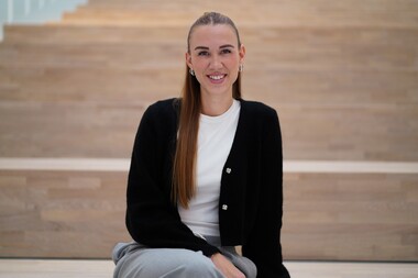 Unsere Junior HR Managerin sitzt auf der Treppe im Otto Group Headquarter im Atrium.