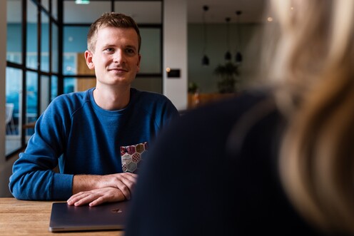 Unser Kollege im Produktmanagement sitzt mit einer Kollegin am Tisch und hört aufmerksam zu