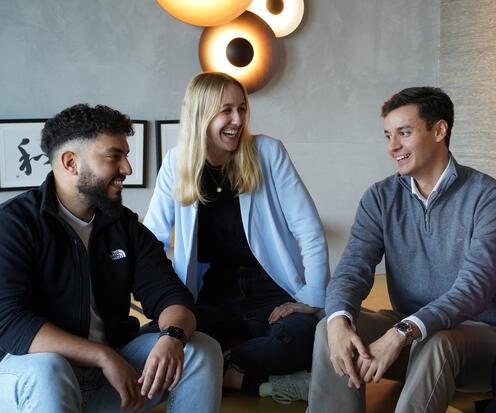 Azubis im Austausch Drei Azubis sitzen zusammen auf dem Sofa reden und lachen gemeinsam.