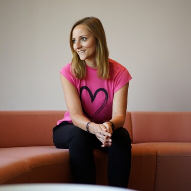 Unsere Kollegin aus der Organisationsentwicklung sitzt auf einem Sofa und lächelt zur anderen Seite