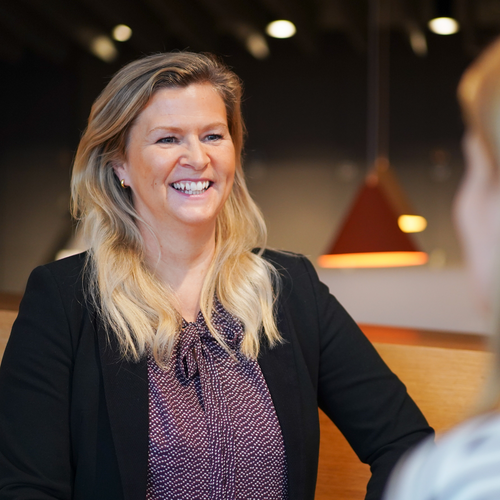 Unsere Teamleiterin im Personalbereich lacht in die Kamera und unterhält sich aufmerksam mit einer Kollegin