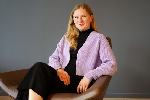 Process Managerin in Diversity und Inclusion sitzt auf einem Sessel und lächelt in die Kamera