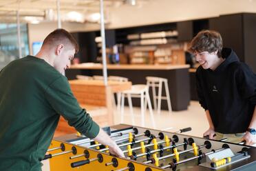 Zwei Azubis spielen konzentriert Tischkicker in einem unserer Social Spaces im OTTO-Headquarter