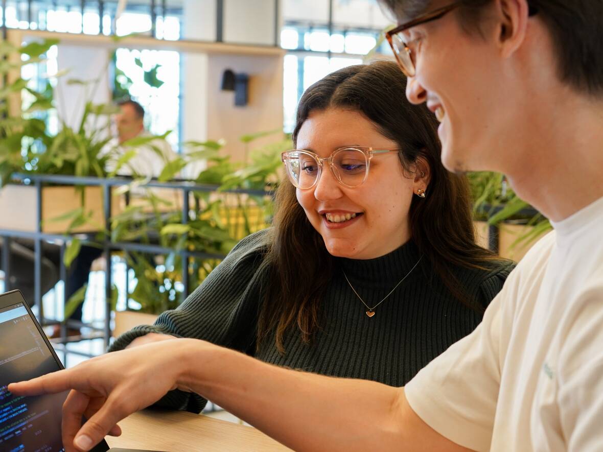 Zwei Azubis schauen sich gemeinsam Code an im Social Space. 