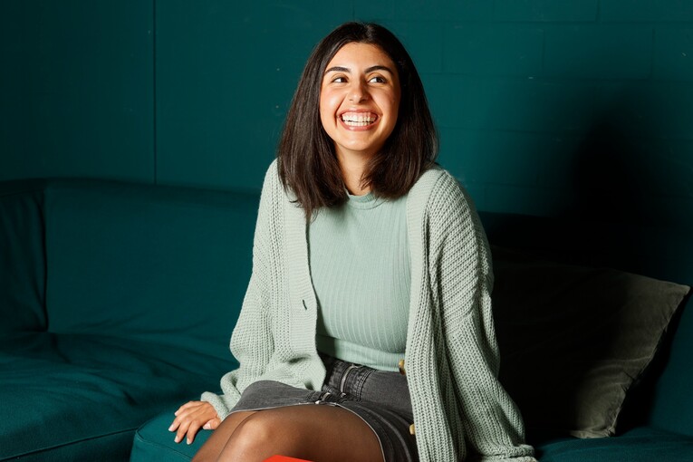 Software Entwicklerin sitzt auf einem grünen Sofa Sie hat ihren Berufseinstieg als Software Entwicklerin bei OTTO gemacht. Sie sitzt auf einem grünen Sofa im Co-Working-Space von OTTO und lächelt zur Seite.