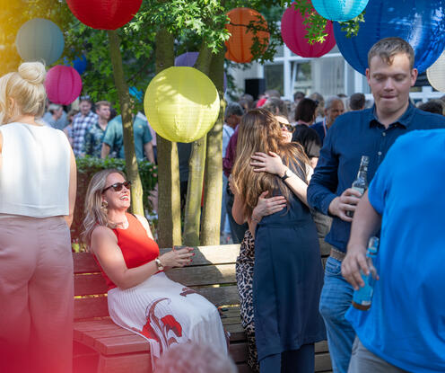 75 Jahre OTTO Geburtstagsfeier Viele Menschen, umgeben von farbenfrohen Lampions, stehen bei gutem Wetter in guter Stimmung zusammen. Einige unterhalten sich mit einer Flasche in der Hand. Im Hintergrund tummeln viele Menschen umher und genießen auch die Feierlichkeiten für das 75-jährige Bestehen des OTTO-Versandhandels