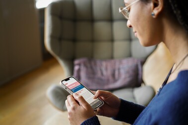 Unsere Kollegin schaut auf ihr Handy und scrollt auf der Karriereseite von OTTO.