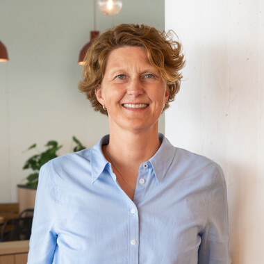 Führungskraft bei OTTO Unternehmensstrategie Führungskraft im Bereich Unternehmensstrategie steht im Social Space hat die Hände in der Hose und lächelt in die Kamera