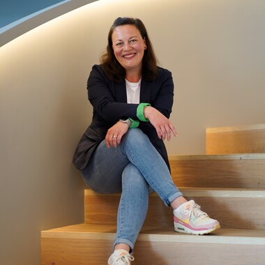 Technical Writerin Teil der ersten Staffel Role Models in Tech sitzt lächelnd auf Treppe.