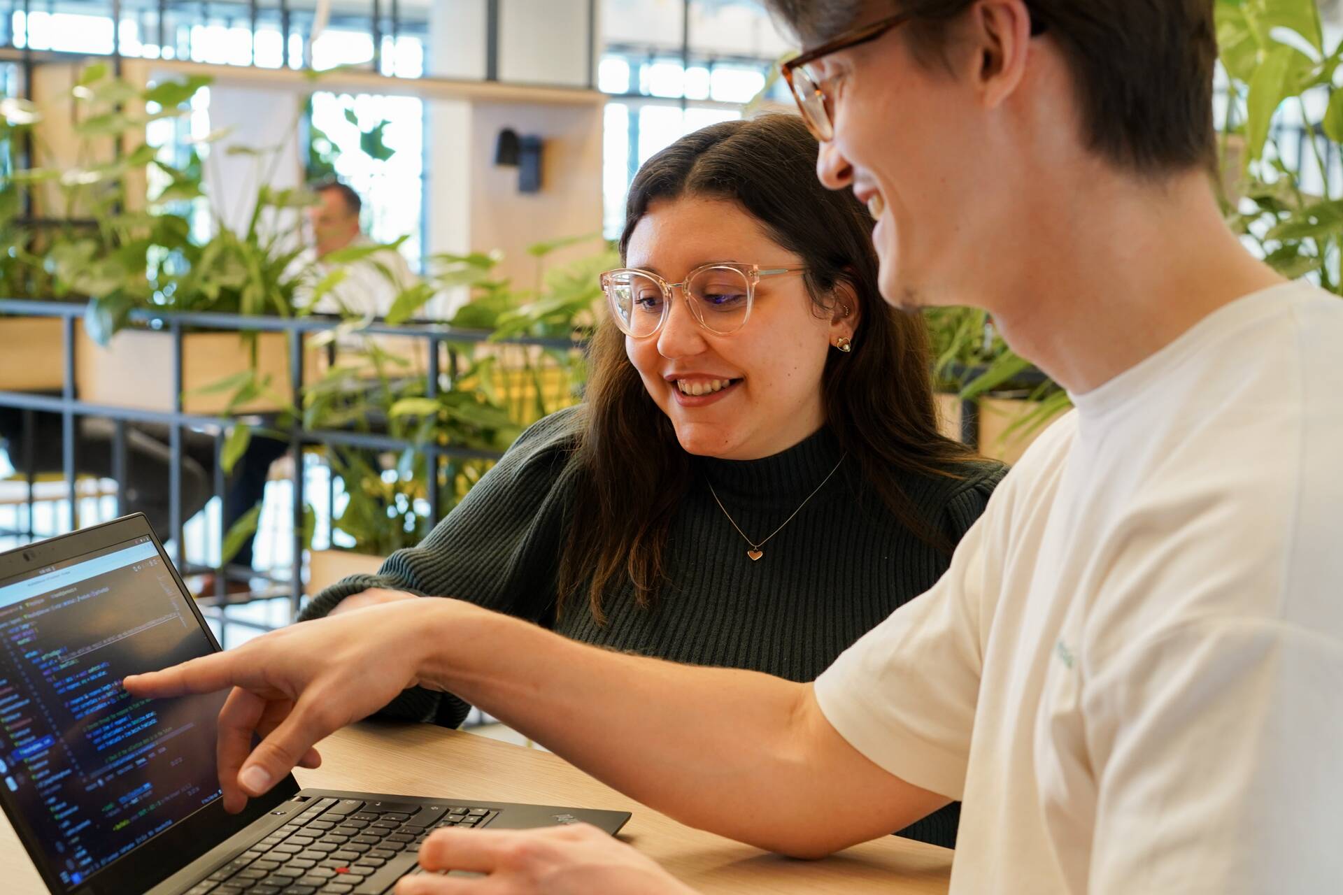Zwei Azubis schauen sich gemeinsam Code an im Social Space. 