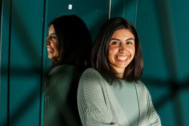 Sie hat ihren Berufseinstieg als Software Entwicklerin bei OTTO gemacht. Sie steht im Co-Working-Space und lächelt seitlich in die Kamera.