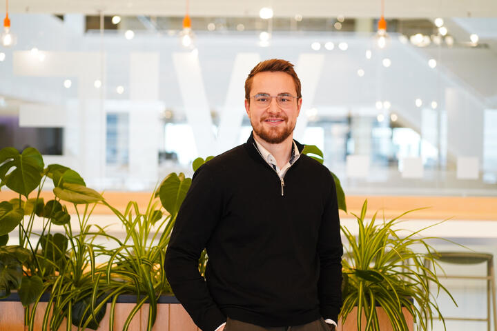 Unser Kollege lächelt in die Kamera Unsere Kollege steht vor mehreren Pflanzen und lächelt in die Kamera und befindet sich in einen unserer Social Spaces