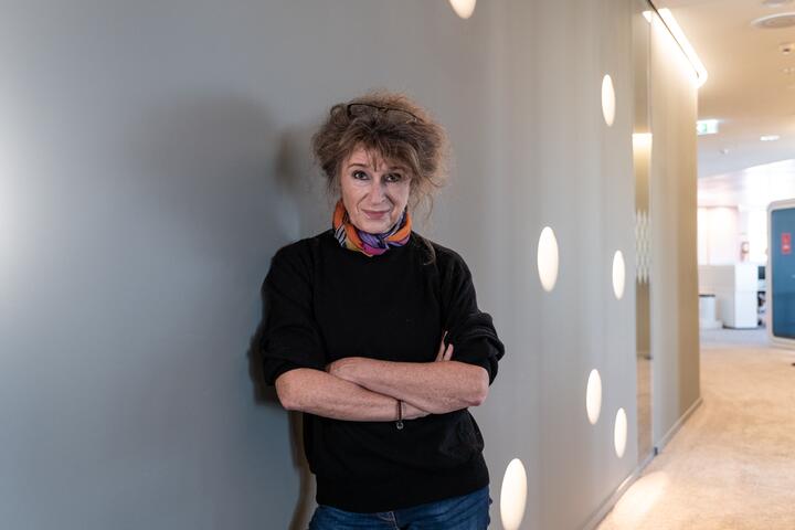 Unsere Kollegin lächelt mit verschränkten Armen in die Kamera Unsere Kollegin ist an einer weißen Wand angelehnt und lächelt mit verschränkten Armen in die Kamera.