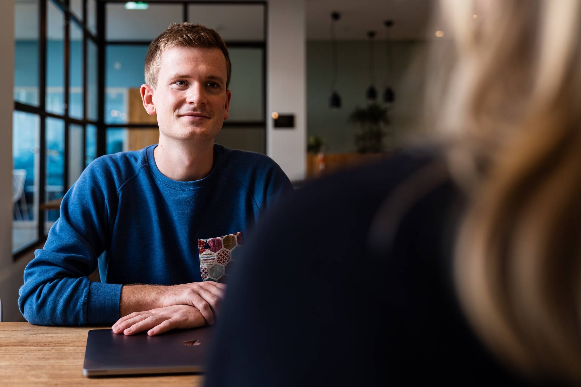 Unser Kollege im Produktmanagement sitzt mit einer Kollegin am Tisch und hört aufmerksam zu