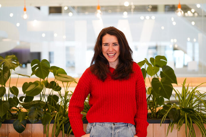 Unsere Kollegin lächelt in die Kamera Unsere Kollegin lächelt in die Kamera und im Hintergrund sind mehrere Pflanzen zu sehen.