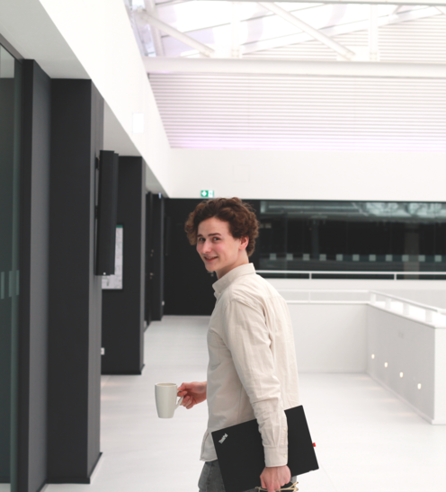 Timon mit Laptop im Büro auf dem Weg zu einem Meeting